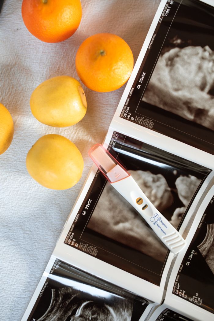 Pregnancy ultrasound images beside citrus fruits and a positive test, symbolizing new life.